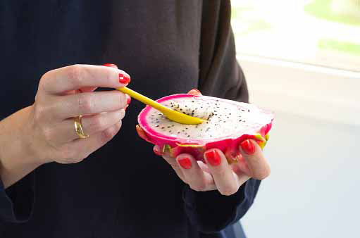 young person eating dragon fruit pulp with spoon
